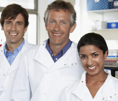 Multiethnic team of three scientific specialists smiling at the camara in a laboratory