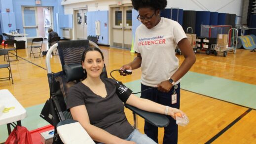 Female blood donor in donation chair having her blood pressure taken by a male phlebotomist in preparation for a blood donation at a New York Blood Center mobile blood drive.
