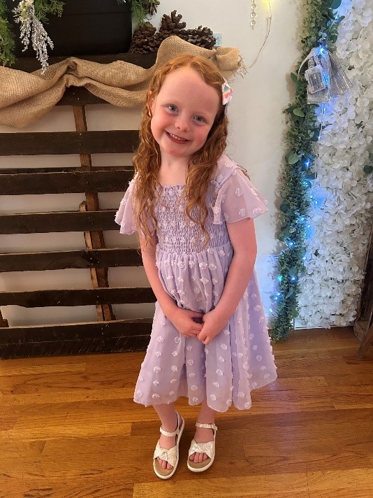 Ellora smiling in a dress.