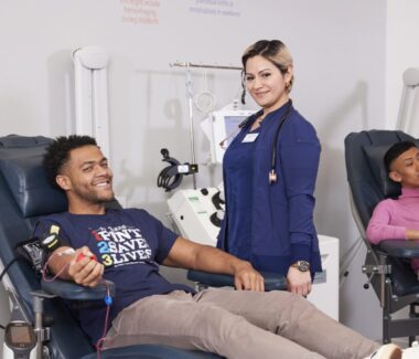 Smiling RIBC phlebotomist attending to blood donor.