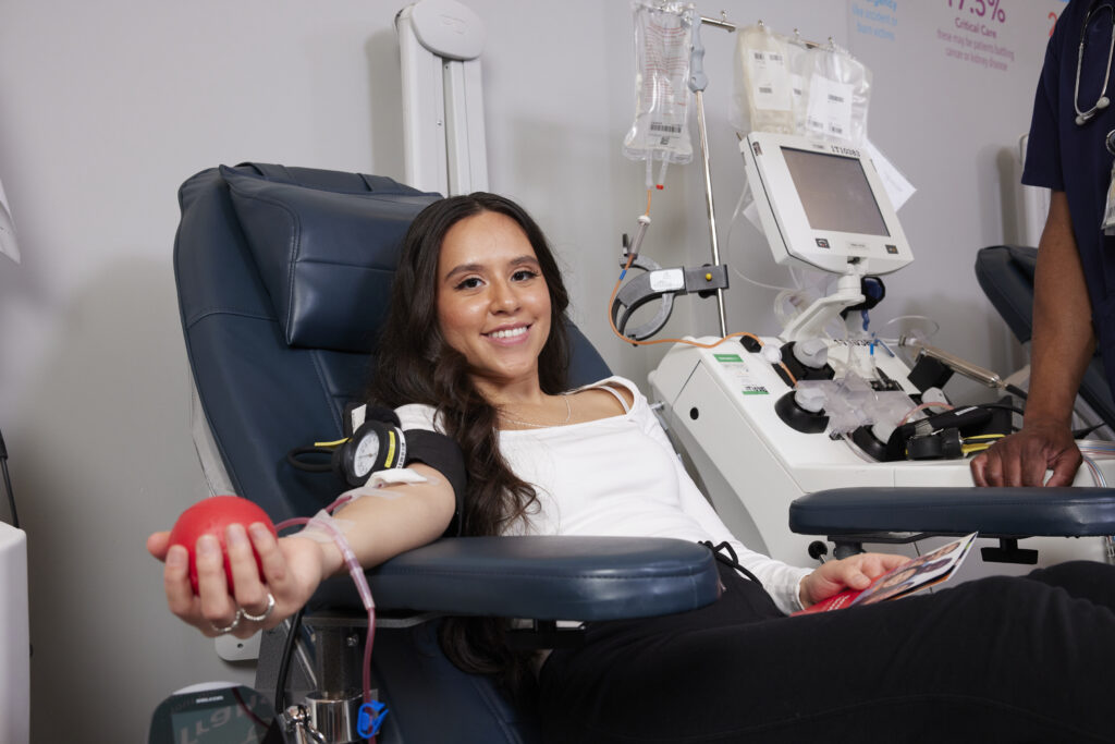 Smiling blood donor holding red foam ball as she donates