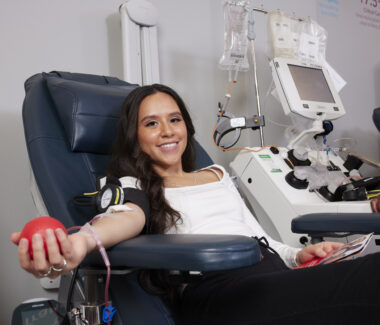 Smiling blood donor holding red foam ball as she donates