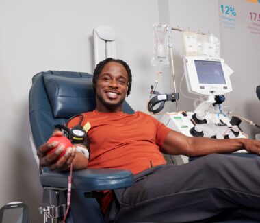 Smiling blood donor squeezing a red foam heart
