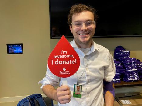 Smiling donor holding up a red sign that reads, "I'm awesome, I donate!"