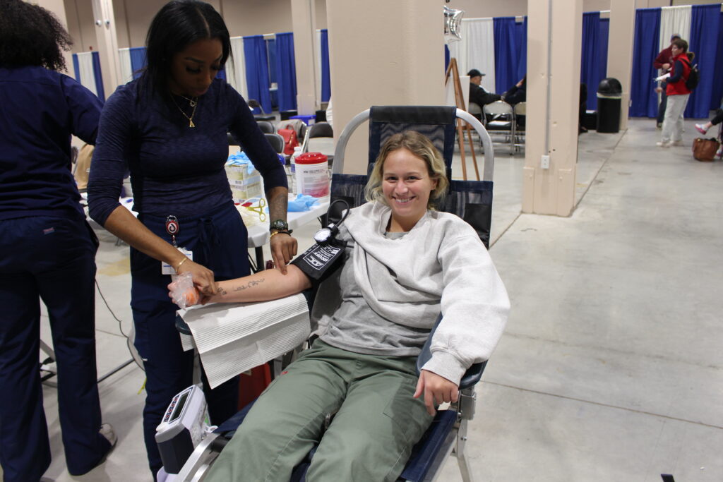 Smiling blood donor giving blood as attended to by BBD staff member.