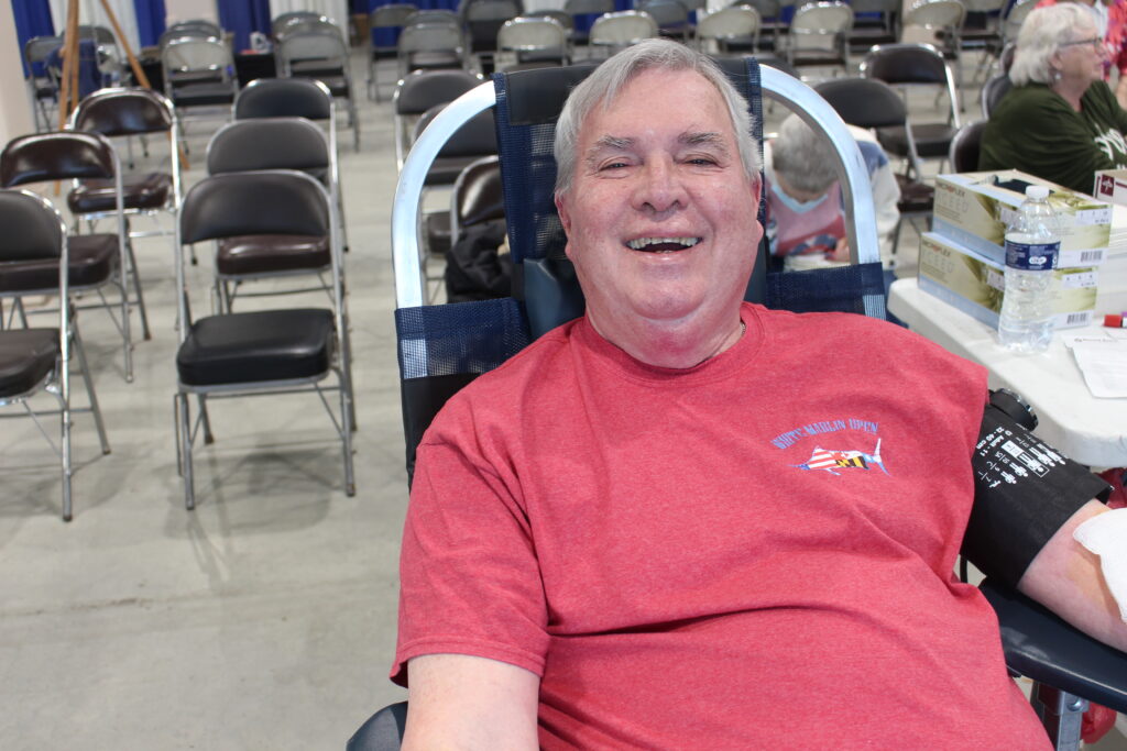 A smiling blood donor wearing a red shirt.