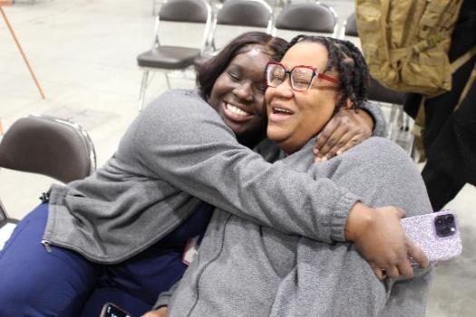 Two BBD staff members smiling and sharing a hug.