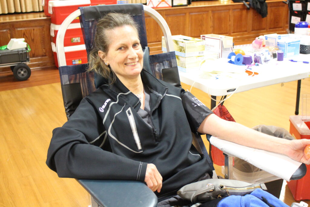 Smiling blood donor giving blood at blood drive.