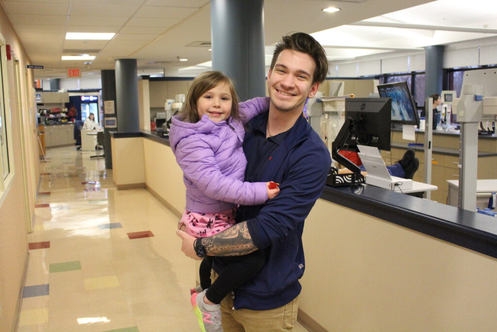 Smiling blood donor with his child at the Christiana Donor Center.