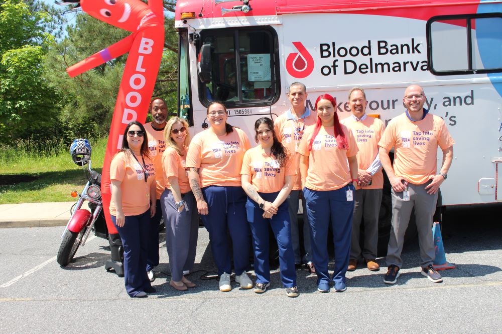 BBD staff posing in front of the mobile bus at Dogfish Head Brewery Blood for a Brew Blood Drive.