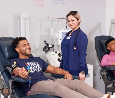 Smiling male donating blood being attended to by NCBB phlebotomist.