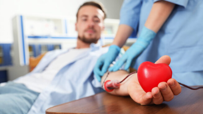 Young man donating blood at a Community Blood Center with a foam heart in his hand.
