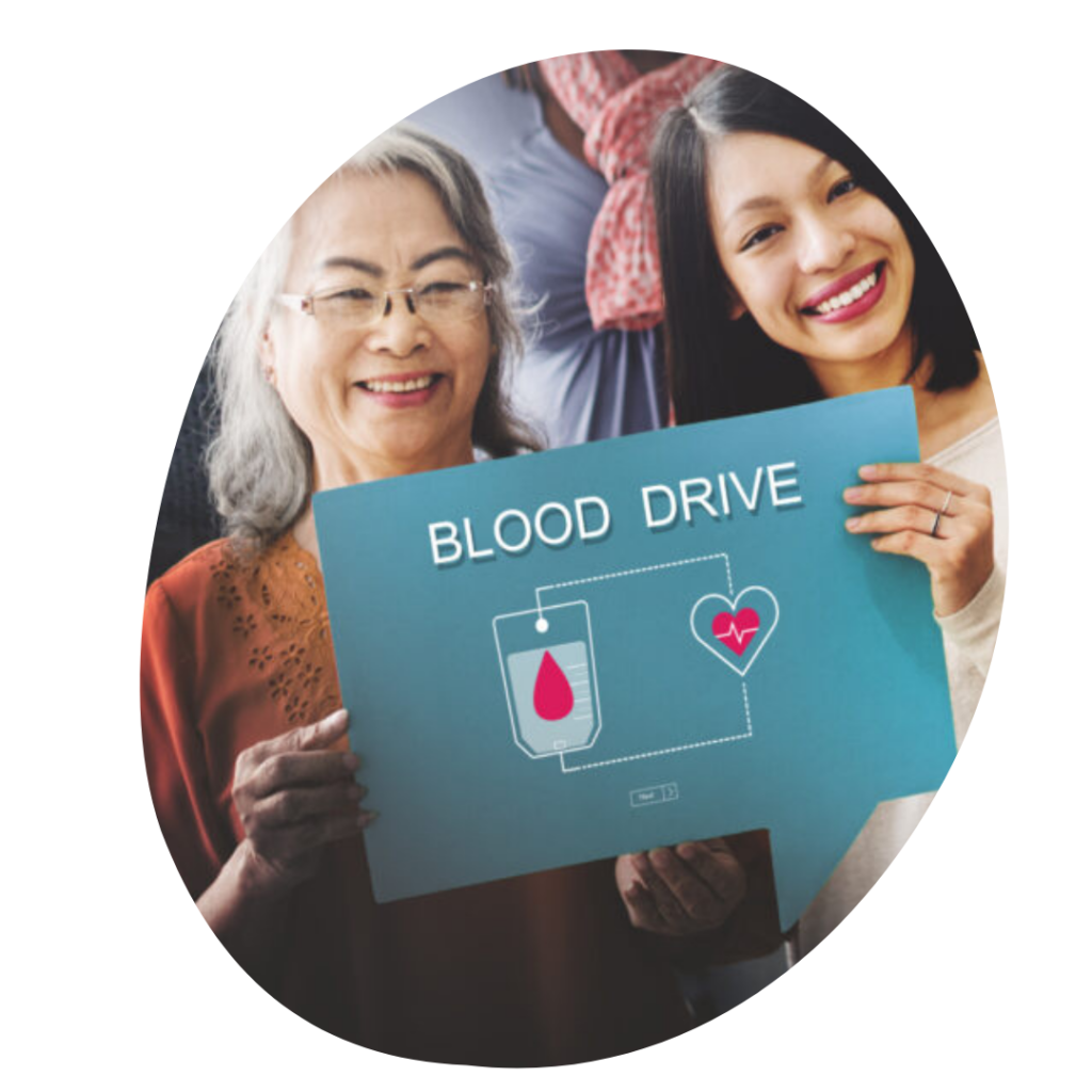 Two women of Asian descent holding a sign up reading Blood Drive.