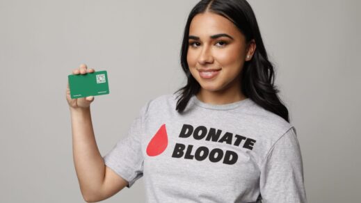 Blood donor holding her Loyalty Rewards card wearing a t-shirt reading Donate Blood.