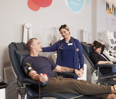 Blood donor in donation chair while being attended to by MBC phlebotomist.